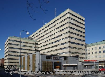 Centralblocket och Akutmottagningen på Universitetssjukhuset i Lund 2011-02-12.
Centralblocket reser sig högt, och till höger i fonden skymtar DE-blocket (expeditioner och laboratorier) bakom akutmottagningen
Nyckelord: Universitetssjukhus; USiL; SUS; Lund; Centralblock; Exteriör; DE-block; Akut; Akutmottagning; Mottagning