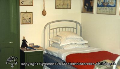 Medicinhistoriska museet. Foto, kopia gjord 18/sep/96. Foto från utställning av sköterskerum. Jfr bildfil SMHS110125-039, eller SMHS110125-042. 
Medicinhistoriska museet. Foto, kopia gjord 18/sep/96. Foto från utställning av sköterskerum. Jfr bildfil Jfr SMHS 110127-003, SMHS110125-039, eller SMHS110125-042. 
- Rimligen ett foto från en utställning på medicinhistoriska museet i Lund i slutet av 1900-talet, visande ett rum för en sköterske-elev på SSSH. 
Nyckelord: Medicinhistoriskt;Museum;Sköterska;Sjuksköterska;SSSH;Sovrum;enkelt;bostadsrum;Elev;Elevrum;utställning;Medicinhistoriskt;Museum;Lund;Kapsel 07