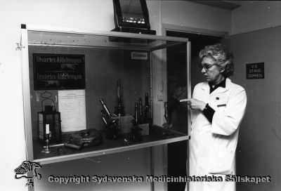 Medicinhistorisk utställning seminariets bottenvåning nov. 1986. 
Medicinhistoriska samlingar i Lund. Utställning seminariets bottenvåning nov. 1986. Foto: Ernst von Scheele.
Sjuksköterskan Agnete Bisgaard (1925-1996) arbetade för museet och Sydsvenska Medicinhistoriska Sällskapet från 1985. Hon hjälpte till med utställningar, hon katalogiserade böcker och hon var "husfru" fram till sin pensionering.
Nyckelord: Medicinhistoriskt;Museum;Lund;Seminariet;Mikroskop;Skylt;Invärtes;Utvärtes;Afdelning;Kapsel 07