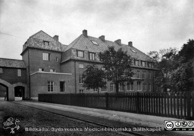 1918 års byggnad vid Lasarettet i Lund med radiologisk klinik, kirurgisk vårdavdelning och kirurgisk poliklinik
År 1918 flyttade den radiologiska avdelningen in på den andra våningen i detta nybyggda hus (foto 1918). Både röntgendiagnostik och viss röntgenbehandling skedde i det. Bottenvåningen hyste fram till 1960-talet kirurgisk poliklinik och sjukhusets administration. På den s.k. mansardvåningen (tredje våningen) fanns kirurgiska vårdplatser och personalrum. Från 35mm repronegativ lasarettsfotograferna i Lunds arkiv. Pärm "Gammalt A".
Nyckelord: Lund;Lasarett;Universitet;Universitetssjukhuset;Röntgen;Kirurgi;Poliklinik;Privatavdelning;Direktion;Administration