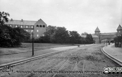 Allhelgona Kyrkogata österut. Vy mot den 1918 nybyggda ovanjordiska kulverten med sina två valv tillsammans med Kvinnokliniken
Gatan ser ut att vara under byggande, och man ser en eller kanske två skottkärror på den. Lyktstolparna tycks ännu inte ha fått sina lamphus. Foto rimligen 1918 eller något år senare. Från lasarettsfotograferna i Lunds arkiv. Pärm "Gammalt A".
Nyckelord: Lasarettet;Lund;Universitet;Universitetssjukhus;Kulvert;Kvinnoklinik;Gata