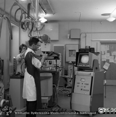 Docent Tord Olin på experimentalröntgen i Lund 1969
Pärm "USiL div. tagningar 1960 och t.v.". Experimentalröntgen 1969. Docent (senare professor i Malmö) Tord Olin med röntgenassistent Britt Nihlén vid en röntgenapparat med elektronisk bildförstärkare och monitor. Från negativ
Nyckelord: Lund;Lasarett;Universitet;Universitetssjukhus;Rtg;Experimentalröntgen;Angiografi;Bildförstärkare