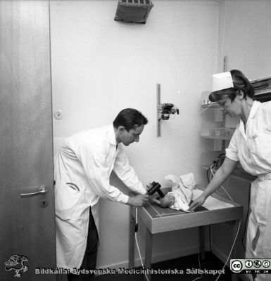 Neonatologen Nils Svenningsen på barnkliniken i Lund 1969
Pärm "USiL div. tagningar. 1960 och t.v.". 1969. Omärkt bild. Från negativ. Neonatologen docent Nils Svenningsen mäter något på ett spädbarn.
Nyckelord: Lund;Lasarett;Universitet;Universitetssjukhus;Neonatologi;Pediatrik;BB;KK