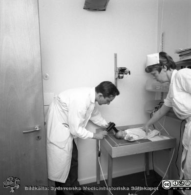 Neonatologen Nils Svenningsen på barnkliniken i Lund 1969
Pärm "USiL div. tagningar. 1960 och t.v.". 1969. Omärkt bild. Från negativ. Neonatologen docent Nils Svenningsen mäter något på ett spädbarns skalle.
Nyckelord: Lund;Lasarett;Universitet;Universitetssjukhus;Neonatologi;Pediatrik;BB;KK