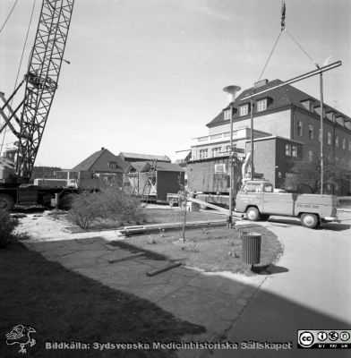 Forskningsbaracken på innergården i den tidigare medicinska kliniken tas bort
Pärm "USiL div. tagningar. 1960 och t.v.". Foto 1968. Från negativ. - Bildserien visar rimligen borttagningen av den barack med forskningsutrymmen som något decennium tidigare hade satts på en av mediciniska klinikens innergårdar. Medicinska klinkiken hade 1968 flyttat in i det nya centralblocket, vilket bör ha varit skälet till att baracken togs bort.
Nyckelord: Lund;Lasarett;Sjukhus;Universitet;Universitetssjukhus;Intern;Medicin;Klinik;Forskning;Barack