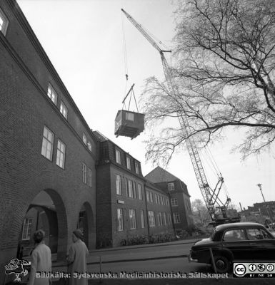 Forskningsbaracken på innergården i den tidigare medicinska kliniken tas bort
Pärm "USiL div. tagningar. 1960 och t.v.". Foto 1968. Från negativ. - Bildserien visar rimligen borttagningen av den barack med forskningsutrymmen som något decennium tidigare hade satts på en av mediciniska klinikens innergårdar. Medicinska klinkiken hade 1968 flyttat in i det nya centralblocket, vilket bör ha varit skälet till att baracken togs bort.
Nyckelord: Lund;Lasarett;Sjukhus;Universitet;Universitetssjukhus;Intern;Medicin;Klinik;Forskning;Barack