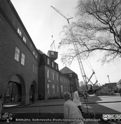 Forskningsbaracken på innergården i den tidigare medicinska kliniken tas bort
Pärm "USiL div. tagningar. 1960 och t.v.". Foto 1968. Från negativ. - Bildserien visar rimligen borttagningen av den barack med forskningsutrymmen som något decennium tidigare hade satts på en av mediciniska klinikens innergårdar. Medicinska klinkiken hade 1968 flyttat in i det nya centralblocket, vilket nog var skälet till att baracken togs bort.
Nyckelord: Lund;Lasarett;Sjukhus;Universitet;Universitetssjukhus;Intern;Medicin;Klinik;Forskning;Barack