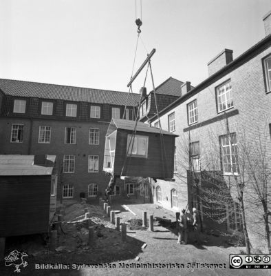 Forskningsbaracken på innergården i den tidigare medicinska kliniken tas bort
Pärm "USiL div. tagningar. 1960 och t.v.". Foto 1968. Från negativ. - Bildserien visar rimligen borttagningen av den barack med forskningsutrymmen som något decennium tidigare hade satts på en av mediciniska klinikens innergårdar. Medicinska klinkiken hade 1968 flyttat in i det nya centralblocket, vilket nog var skälet till att baracken togs bort.
Nyckelord: Lund;Lasarett;Sjukhus;Universitet;Universitetssjukhus;Intern;Medicin;Klinik;Forskning;Barack