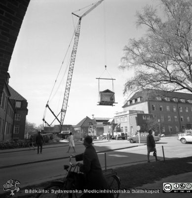 Forskningsbaracken på innergården i den tidigare medicinska kliniken tas bort
Pärm "USiL div. tagningar. 1960 och t.v.". Foto 1968. Från negativ. - Bildserien visar rimligen borttagningen av den barack med forskningsutrymmen som något decennium tidigare hade satts på en av mediciniska klinikens innergårdar. Medicinska klinkiken hade 1968 flyttat in i det nya centralblocket, vilket nog var anledningen till att baracken togs bort.
Nyckelord: Lund;Lasarett;Sjukhus;Universitet;Universitetssjukhus;Intern;Medicin;Klinik;Forskning;Barack