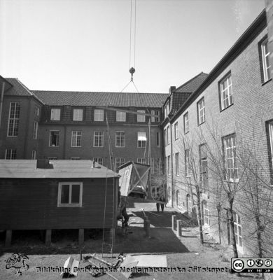 Forskningsbaracken på innergården i den tidigare medicinska kliniken tas bort
Pärm "USiL div. tagningar. 1960 och t.v.". Foto 1968. Från negativ. - Bildserien visar rimligen borttagningen av den barack med forskningsutrymmen som något decennium tidigare hade satts på en av mediciniska klinikens innergårdar. Medicinska klinkiken hade 1968 flyttat in i det nya centralblocket, vilket nog var skälet till att baracken togs bort.
Nyckelord: Lund;Lasarett;Sjukhus;Universitet;Universitetssjukhus;Intern;Medicin;Klinik;Forskning;Barack