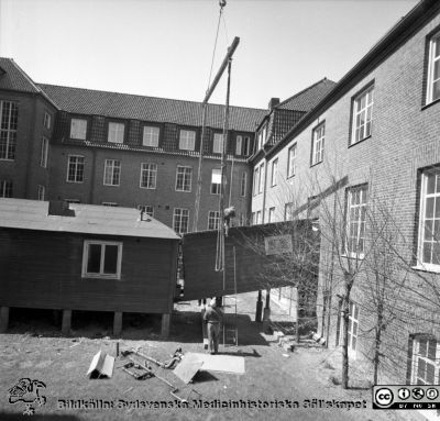 Forskningsbaracken på innergården i den tidigare medicinska kliniken tas bort
Pärm "USiL div. tagningar. 1960 och t.v.". Foto 1968. Från negativ. - Bildserien visar rimligen borttagningen av den barack med forskningsutrymmen som något decennium tidigare hade satts på en av mediciniska klinikens innergårdar. Medicinska klinkiken hade 1968 flyttat in i det nya centralblocket, vilket nog gjorde att baracken togs bort.
Nyckelord: Lund;Lasarett;Sjukhus;Universitet;Universitetssjukhus;Intern;Medicin;Klinik;Forskning;Barack