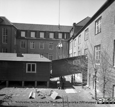 Forskningsbaracken på innergården i den tidigare medicinska kliniken tas bort
Pärm "USiL div. tagningar. 1960 och t.v.". Foto 1968. Från negativ. - Bildserien visar rimligen borttagningen av den barack med forskningsutrymmen som något decennium tidigare hade satts på en av mediciniska klinikens innergårdar. Medicinska klinkiken hade 1968 flyttat in i det nya centralblocket, vilket nog gjorde att baracken togs bort.  Fil SMHS2670 kommer från samma negativ.
Nyckelord: Lund;Lasarett;Sjukhus;Universitet;Universitetssjukhus;Intern;Medicin;Klinik;Forskning;Barack