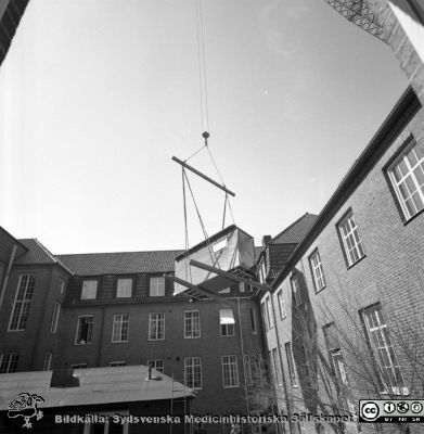 Forskningsbaracken på innergården i den tidigare medicinska kliniken tas bort
Pärm "USiL div. tagningar. 1960 och t.v.". Foto 1968. Från negativ. - Bildserien visar rimligen borttagningen av den barack med forskningsutrymmen som något decennium tidigare hade satts på en av mediciniska klinikens innergårdar. Medicinska klinkiken hade 1968 flyttat in i det nya centralblocket, och baracken behövdes inte mer.
Nyckelord: Lund;Lasarett;Sjukhus;Universitet;Universitetssjukhus;Intern;Medicin;Klinik;Forskning;Barack