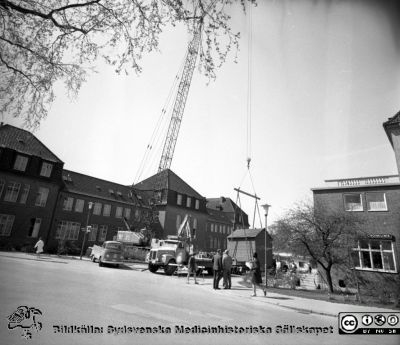 Forskningsbaracken på innergården i den tidigare medicinska kliniken tas bort
Pärm "USiL div. tagningar. 1960 och t.v.". Foto 1968. Från negativ. - Bildserien visar rimligen borttagningen av den barack med forskningsutrymmen som något decennium tidigare hade satts på en av mediciniska klinikens innergårdar. Medicinska klinkiken hade 1968 flyttat in i det nya centralblocket, och baracken behövdes inte längre.
Nyckelord: Lund;Lasarett;Sjukhus;Universitet;Universitetssjukhus;Intern;Medicin;Klinik;Forskning;Barack