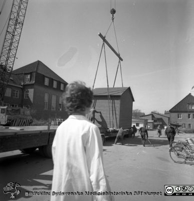 Forskningsbaracken på innergården i den tidigare medicinska kliniken tas bort
Pärm "USiL div. tagningar. 1960 och t.v.". Foto 1968. Från negativ. - Bildserien visar rimligen borttagningen av den barack med forskningsutrymmen som något decennium tidigare hade satts på en av mediciniska klinikens innergårdar. Medicinska klinkiken hade 1968 flyttat in i det nya centralblocket, och rimligen hade ombyggnad av det gamla huset startats.
Nyckelord: Lund;Lasarett;Sjukhus;Universitet;Universitetssjukhus;Intern;Medicin;Klinik;Forskning;Barack