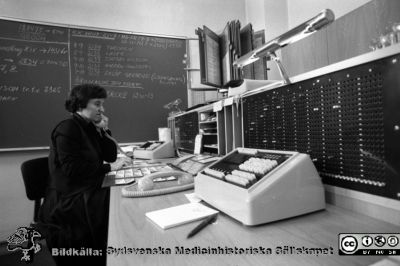 Det s.k. hänvisningsbordet på telefonväxeln på Lasarettet i Lund 1980
Lasarettsfotograferna i Lund. Pärm "Negativ, 80:1." 33. Den anställde ringde 8 och meddelade att hon/han inte var på plats, telefonisten gjorde anteckningar och då någon ringde den aktuella anknytningen plingade det till i hänvisningsbordet och telefonisten kunde lämna besked om när personen träffades. Systemet ersattes senare av hänvisningsdatorer och alla kunde då fixa sina stängningar och medflyttningar själv. Foto 80-02-05. Från negativ.
Nyckelord: Lasarettet;Lund;Universitetssjukhus;USiL;Administration;Telefon;Växel