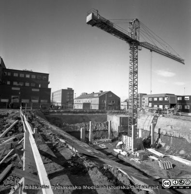 Cetralblocket i Lund byggs 1965
Pärm "Div. tagningar, 1960 och t.v.". Mars, 1965. Centralblocket på Lasarettet i Lund har just börjat byggas. Till vänster i bakgrunden radiologiska kliniken, sedan barnkliniken (långt i bakgrunden), centraltandpolikliniken (närmare), administrationsbyggnaden och byggbaracker. Från negativ.
Nyckelord: Lund;Lasarett;Universitet;Universitetssjukhus;Centralblocket;USiL;Bygge;Grundläggning