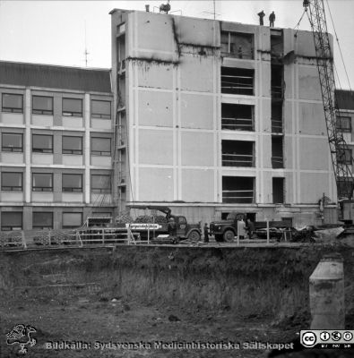 Lasarettet i Lund 1964. Centralblocket byggs
Pärm "Div. tagningar 1960 och t.v.". Foto 1964. AB-blocket byggdes med ett trapphus som var tänkt byggas ihop med den kommande centralbyggnaden (C-huset i Blocket). Här öppnas trapphusets fasad i AB-blocket för den kommande sammanfogningen. Från negativ.
Nyckelord: Lasarettet;Lund;Universitet;Universitetssjukhus;USiL;Bygge