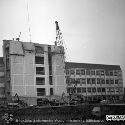 Lasarettet i Lund 1964. Centralblocket byggs
Pärm "Div. tagningar 1960 och t.v.". Foto 1964. AB-blocket byggdes med ett trapphus som var tänkt byggas ihop med den kommande centralbyggnaden (C-huset i Blocket). Här öppnas trapphusets fasad i AB-blocket för den kommande sammanfogningen. Från negativ.
Nyckelord: Lasarettet;Lund;Universitet;Universitetssjukhus;USiL;Bygge