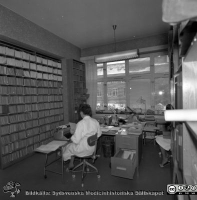 Lasarettet i Lund år 1967. Öronklinikens expedition.
Lasarettsfotograferna. Lund. Pärm "Div. tagningar, 1960 och t.v.". Fotgo 1967. Sekreterare på öronklinikens skrivexpedition och journalarkiv. Personerna har inte identifierats. Från negativ.
Nyckelord: Lund;Lasarett;Universitet;Universitetssjukhus;USiL;Öron;ÖNH;Öron-näsa-hals;Otologi;Otiatri;Administration;Sekreterare;Expedition