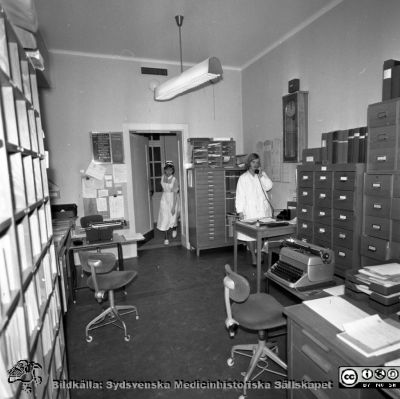 Lasarettet i Lund år 1967. Öronklinikens expedition.
Lasarettsfotograferna. Lund. Pärm "Div. tagningar, 1960 och t.v.". Foto 1967. Skrivexpedition och journalarkiv på öronkliniken. Personerna i bilden har inte identifierats. Från negativ
Nyckelord: Lund;Lasarett;Universitet;Universitetssjukhus;USiL;Öron;ÖNH;Öron-näsa-hals;Otologi;Otiatri;Administration;Sekreterare;Expedition