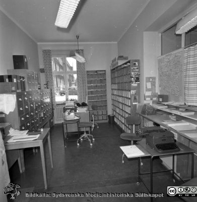 Lasarettet i Lund år 1967. Öronklinikens expedition.
Lasarettsfotograferna. Lund. Pärm "Div. tagningar, 1960 och t.v.". Foto 1967. Sekreterare på öronklinikens skrivexpedition och journalarkiv. Från negativ
Nyckelord: Lund;Lasarett;Universitet;Universitetssjukhus;USiL;Öron;ÖNH;Öron-näsa-hals;Otologi;Otiatri;Administration;Sekreterare;Expedition