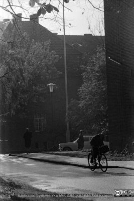 Höstlig vy 1961 vid dåvarande medicinska klinikens östra gavel, mot sydväst
Lasarettsfotograferna. Lund. Pärm "Div. tagningar, 1960 och t.v.". Lasarettets exteriörer, 1960-talet.  Dåvarande kvinnokliniken i fonden. Foto 1961. Från negativ.
Nyckelord: Lasarett;Lund;Universitet;Universitetssjukhus;USiL;Medicin;Kvinnoklinik;Klinik;Cyklist;Höst