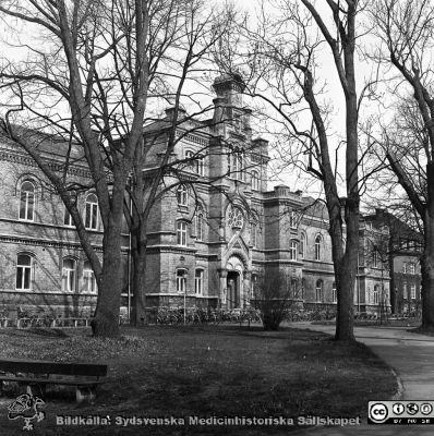 Fasad mot öster på 1867 - 68 års kirurgiska klinik i Lund
Sjukhusfotograferna i Lund. Pärm Negativ 1981:1.	58. Gamla kirurgiska kliniken från sydost, byggd 1867-68 och nu sedan ~10 år i Lunds Universitets ägo och använd som studentcentrum. Foto: ER. Från negativ.
Nyckelord: Lasarettet;Lund;Universitetssjukhuset;USiL;Kirurgisk;Klinik;Administration