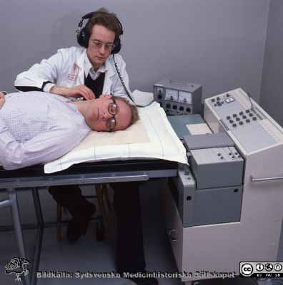 En tidig ultraljudsundersökning
Sjukhusfotograferna i Lund. Pärm negativ, 1979:1. Neurologen Bo Norrving  gör ultraljudsdoppler på A. carotis den första i Skandinavien. "Patienten" är en kollega, Kjeld Hougaard. 45. 79-04-23. Från positiv.
Nyckelord: Lasarettet;Lund;Universitetssjukhus;USiL;Ultraljud;Undersökning;Doppler;Laboratorium