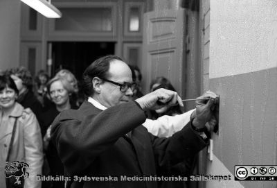 Neurokirurgisk fest 1976
Sjukhusfotograferna i Lund. Pärm Negativ, S/V. 1976.	145. Neurokirurgisk fest, 8/10-76 då de två neurokirurgiska klinikerna i Lund slogs samman till en enda, tillika 30-årsjubileum av det första neurokirurgiska ingreppet i Lund (av prof. Nils Lundberg). Nils Lundbergs efterträdare, Carl-Axel Thulin drar i nästa skruv i den dagens minnesplakett. Från negativ.
Nyckelord: Lasarett;Lund;Universitetssjukhus;Universitet;USiL;Neurokirurgi;Fest