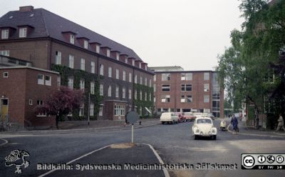 Vy norrut från valven mellan reumatologiska och medicinska klinikerna
Pärm Lasarettsfoto, interiörer och exteriörer m.m. 1958-1960. Foto 1960. Öronkliniken till vänster och radiologiska kliniken i bakgrunden. Ortopediska kliniken skymtar bakom träden till höger. Från negativ
Nyckelord: Lasarett;Lund;Universitet;Universitetssjukhus;USiL;Radiologi;Onkologi;Ortopedi;_Öron;_ÖNH;Klinik;Bygge