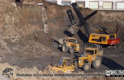 Grävning för det blivande centralblocket
Pärm Lasarettsfoto, interiörer och exteriörer m.m. 1958 - 1960. Gropen grävs för C-blocket hitom fasaden på AB-blocket. Hålet var djupt, och de stora maskinerna ser ut som leksaker. Foto 1960. Från negativ. 
Nyckelord: Lund;Lasarett;Universitet;Universitetssjukhus;USiL;Blocket;Bygge;Grävning