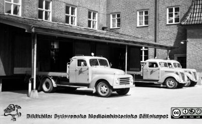 Lastbilar vid utlastningsbryggan för matlådor på dåvarande centralköket på södra lasarettsområdet
Pärm Lasarettsfoto, interiörer och exteriörer m.m. 1958 - 1960. 17. Lokaler. Foto 1960. Från negativ.
Nyckelord: Lasarettet;Lund;Universitetssjukhus;USiL;Kök;Transport;Matlåda;Matlådor