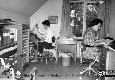 Kontorister på administrationen, Lasarettet i Lund 1960
Pärm Lasarettsfoto, interiörer och exteriörer m.m. 1958 - 1960. 17. Lokaler, Las. 1960. Ulla Larsson till vänster i bild och Barbro Andersson till höger i bild på gamla administrationen vid valven på Allhelgona Kyrkogata på södra lasarettsområdet. Foto rimligen inför flytten till norra lasarettsområdet. Bild SMHS278 kommer från samma negativ och var märkt med namnen. Från negativ.
Nyckelord: Lasarettet;Lund;Universitet;Universitetssjukhus;USiL;Administration;Kontor;Kontorist