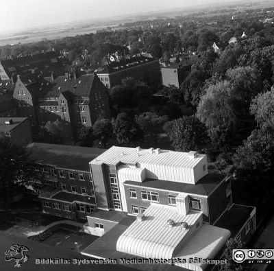 Den nyrenoverade Ögonkliniken A från en våning högt upp i centralblocket
Sjukhusfotograferna i Lund. Pärm Negativ, Dia, 1987. 101/87. Film II. De stora vita takkuporna innehåller nya ventilationsaggregat. Bortom kliniken ses zoologiska och geologiska institutionerna. Från negativ. 
Nyckelord: Lasarettet;Lund;Universitetssjukhus;USiL;Ögon;Oftalmiatrisk;Oftalmologisk;Klinik