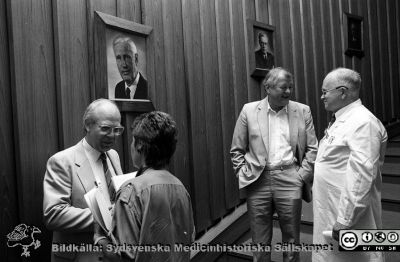Administrativa chefer inför ett möte i aulan på Centralblocket i Lund
Sjukhusfotograferna i Lund. Pärm Svart-vita neg. 1987. 105/-87. 87-08-24. Från vänster sjukhusdirektör Kurt Roos, okänd kvinna, direktionensmedlemmen Torsten Engvall, chefläkaren Hans Rorsman. På väggen porträtt av en rad kirurgprofessorer, närmast Philip Sandblom och Paul Strömbeck. Från negativ. 
Nyckelord: Lasarettet;Lund;Universitetssjukhus;USiL;Administration;Chefer;Möte
