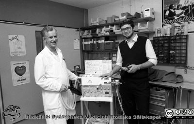 Anestesiologen, docent Lars Nordström och professorn i medicinsk teknik Nils Gunnar Holmer med en ServoVentilator. 
Sjukhusfotograferna i Lund. Pärm Svart-vita neg. 1987. 146/87. Foto i januari 1988.
Nyckelord: Lasarettet;Lund;Universitetssjukhus;USiL;Anestesi;Medicinsk;Teknisk;Klinik;Avdelning;MTA;Ventilator;Respirator