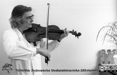 Framträdande på sjukhusets intern-TV-kanal
Sjukhusfotograferna i Lund. Pärm Sv/v neg. 1989.	16. Göran Sundbärg, neurokirurg och skicklig violinist, framträder på sjukhusets intern-TV. Från negativ.
Nyckelord: Lasarettet;Lund;Universitetssjukhus;USiL;Intern-TV;Fiol;Musik;Intern-TV;Solist