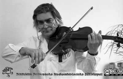 Framträdande på sjukhusets intern-TV-kanal
Sjukhusfotograferna i Lund. Pärm Sv/v neg. 1989.	16. Göran Sundbärg, neurokirurg och skicklig violinist, framträder på sjukhusets intern-TV. Från negativ.
Nyckelord: Lasarettet;Lund;Universitetssjukhus;USiL;Intern-TV;Fiol;Musik;Intern-TV;Solist