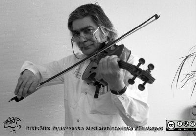 Framträdande på sjukhusets intern-TV-kanal
Sjukhusfotograferna i Lund. Pärm Sv/v neg. 1989.	16. Göran Sundbärg, neurokirurg och skicklig violinist, framträder på sjukhusets intern-TV. Från negativ.
Nyckelord: Lasarettet;Lund;Universitetssjukhus;USiL;Intern-TV;Fiol;Musik;Intern-TV;Solist