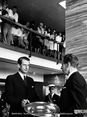 Ceremoni i entréhallen till centralblocket i Lund. 
Bilder från sjukhusprästen Bernt Eriksson, 1960 - 2000-talen. Hagblom Foto men i övrigt omärkt bild.  Fakultetens dekanus 1968 - 1977, professor Bengt Borgström, och landshövding (1961-1973) Gösta Netzén vid en ceremoni i entréhallen till centralblocket i Lund. Möjligen vid centralblockets invigning 1968. Från foto. 
Nyckelord: Lasarettet;Lund;Universitetssjukhus;USiL;Ceremoni;Invigning;Centralblocket