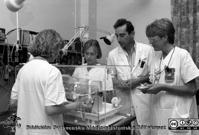 Docent Nils Svenningsen vid en kuvös
Pärm Lasarettsfotograferna i Lund, negativ, 1991. 34. 91-07-24. Barn, 94. Docent Nils Svenningsen vid en kuvös tillsammans med sköterskor. Identiteten på dem är osäker. Med ryggen mot kameran kanske Inger Lomander eller Ulla Ganestam. Lena Andersson till vänster om Nils Svenningsen. Till höger troligen sjuksköterskan Eva-Karin Håkansson. Från negativ. 
