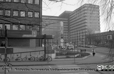 Centralblocket från huvudingången. 
Lasarettsfotograferna i Lund, pärm S/V negativ, 1992. 17. Patienthotellet till vänster med bl.a. Sparbankens kontor. Tandpolikliniken till höger. 92/06. Från negativ.
Nyckelord: Lasarettet;Lund;USiL;Universitetssjukhuset;Patient;Hotell;Sparbank;Centralblocket;Entr;Tandöpoliklinik