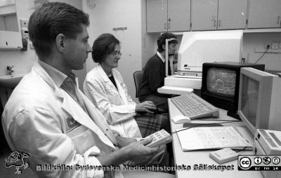 Docenterna Jörgen Larsson och Birgitta Bauer på ögonkliniken i Lund
Lasarettsfotograferna i Lund,  pärm S/V Neg. 1996. 96. 6. Ögonkliniken. Foto vid en Rodenstock ögonbottenkamera och tillhörande dator. Apparaten motsvarade inte förväntningarna och försvann snart. Från negativ.
Nyckelord: Lasarettet;Lund;Universitetssjukhuset;USiL;Ögonklinik;Oftalmologisk;Kamera;Fundus;Ögonbotten