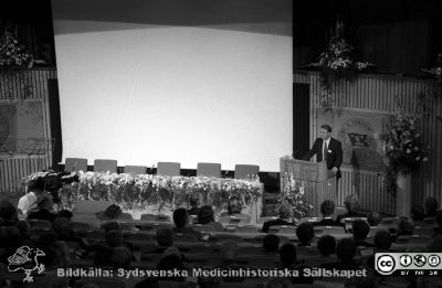 Forskningens Dag 1996 med temat "Att stå, gå och falla - vad är balans?". 
Lasarettsfotograferna i Lund,  pärm  Sv/v Neg, 1996. 56, 96. Fernströmssymposium i aulan. Öronläkaren och balansforskaren docent (senare professor) Måns Magnusson i talarstolen. Från negativ.
Nyckelord: Lasarettet;Lund;Forskning;Forskningens Dag;Universitetssjukhuset;USiL;Möte;Symposium