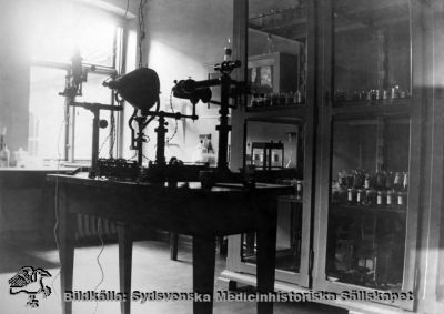 Ögonkliniken i Lund på södra lasarettsområdet i mitten på 1920-talet
Ett apparat- och preparatrum på ögonklinikne i Lund i mitten av 1920-talet. Längst bort på bordet står ett Gullstrands stora binokulära reflexfria oftalmoskop. De andra apparatena på bordet är inte identifierade. 
Foto Alfr. Hagblom, Lund i mitten på 1920-talet till ett fotoalbum för professor Gustaf Ahlström när han pensionerades år 1927.
Nyckelord: Ögon;Ögonklinik;Oftalmologi;Oftalmiatrik;Lund;Lasarett;Södra;Område;