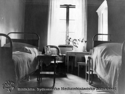 Ögonkliniken i Lund på södra lasarettsområdet i mitten på 1920-talet
Rum för 2 patienter, s.k. halvenskilt rum, på ögonkliniken i Lund i mitten på 1920-talet. Bilden finns publicerad i A. Flaum 1968 på sid 165, och anges där vara tagen omkring 1900, vilket inte förefaller trovärdigt eftersom den nu kan konstateras sitta i ett album producerat för professor Gustaf Ahlström inför hans pensionering 1927. Det skänktes  år 2010 av dennes sonson Kristian Ahlström till Sydsvenska Medicinhistoriska Sällskapet.
Foto Alfr. Hagblom, Lund
Nyckelord: Ögon;Ögonklinik;Oftalmologi;Oftalmiatrik;Lund;Lasarett;Södra;Område;