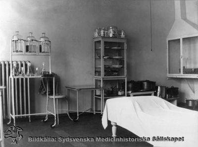 Ögonkliniken i Lund på södra lasarettsområdet i mitten på 1920-talet
Ett undersökningsrum och laboratorium på ögonkliniken i Lund i mitten på 1920-talet. Professorn, Gustaf Ahlström, gjorde själv bakterieodlingar och mikroskopiska undersökningar, och inredningen med ett dragskåp och utrustningen i bakgrunden talar för att detta är den lokal där prover togs och bearbetades.
Foto Alfr. Hagblom, Lund för ett fotoalbum tillägnat professor Gustaf Ahlström när han pensionerades år 1927.
Nyckelord: Ögon;Ögonklinik;Oftalmologi;Oftalmiatrik;Lund;Lasarett;Södra;Område;