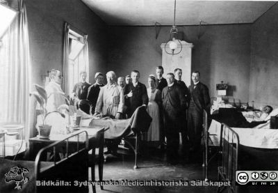 Professor Seved Ribbing går rond på gamla medicinska kliniken år 1900. 
Ur pärm med bilder tänkta för A. Flaum "Lasarettet i Lund" (1968). Märk kakelugnen och gaslampan: i mitten Sophiasystern, syster Inez. Bilden erhållen av fru Ingrid Karlow, Saltsjö-Duvnäs. (Sid.198)
Nyckelord: Lasarettet;Lund;Universitetssjukhuset;USiL;Medicinsk;Klinik;Invärtes