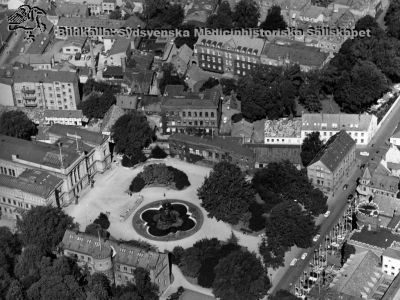 Flygfoto av universitetsplatsen i Lund, från sydost
Flygfoto av universitetsplatsen, efter 1959 då sfinxerna på universitetshuset togs ned, och senast 1968 då bilden publicerades. Runt Universitetspatsen ser man universitetets huvudbyggnad, Palaestra, fontänen och Lundagårdshuset. Till höger ses anatomicum (theologicum då bilden togs, senare arkeologisk institution), kurhuset med tillbyggnad,östra envåningslängan (förut ekonomibyggnad), portvaktshuset och gamla patologiska institutionen. I bakgrunden från höger kirurgiska kliniken, gamla ögonkliniken, lungkliniken. Lunds universitets historiska museum. Publicerad på sid 204 i A. Flaum "Lasarettet i Lund 1768 - 1968", Lund 1968. 
Nyckelord: Lund;Universitetsplatsen;Universitet;Flygfoto;Palaestra;Odeum;Patologisk;Institution;Lundagård;Anatomicum;Theologicum;Arkeologisk;Portvakt;Kirurgisk;Ögonklinik;Lungklinik;